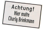 Gemaltes Schild mit der Aufschrift: Achtung! Hier malte Charly Brinkmann